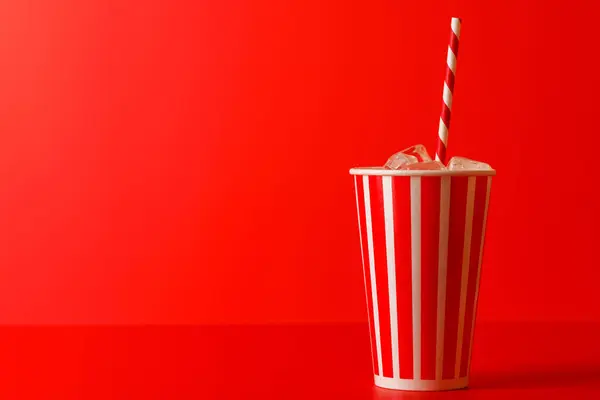 Paper cup with cola and ice over red background, with copy space