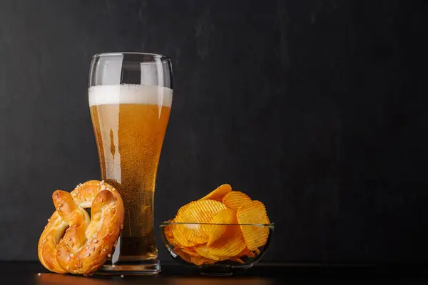 Beer, chips and pretzel. Over dark background with copy space