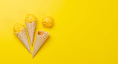 Lezzetli waffle külahlarında limonlu dondurma, her tat için bir ikram. Fotokopi alanı olan sarı arkaplan üzerinde düz uzanır