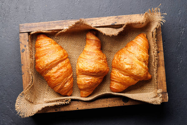 Fresh croissants in wooden box. Flat lay