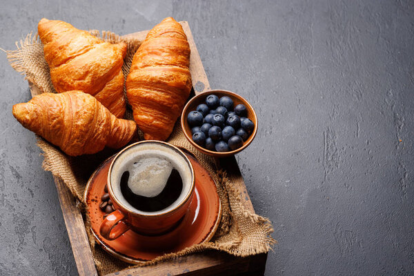 Cappuccino coffee and fresh croissants on stone table. With copy space