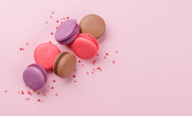 Çeşitli renkte badem kurabiyeleri. Aşk tatlıları pembe arkaplanda fotokopi alanı ile