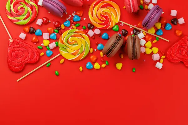 Verschiedene Bunte Bonbons Lutscher Und Makronen Flach Über Rotem Hintergrund Stockbild