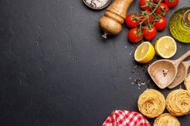 Yemek sahnesi: kiraz domatesleri, makarna, masada baharatlar. Kopyalama alanı olan düz