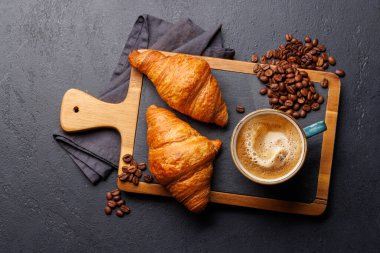 Cappuccino kahve ve taş masada taze kruvasan. Düz yatıyordu