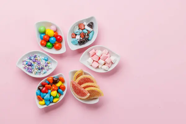 Divers Bonbons Colorés Sucettes Pose Plate Sur Fond Rose Avec Photo De Stock