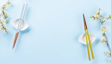 Kiraz çiçeği dalı ve yemek çubuklarıyla süslenmiş masa, Japon yemek kültürünün somut örneği, geniş bir kopya alanı sağlıyor.