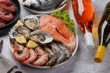 Deniz ürünleri tabağı, karides, somon, istiridye. Şarap şişesiyle.