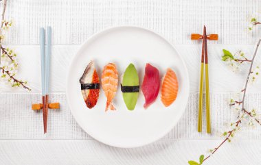 Masadaki suşi tabağı kiraz çiçeği dalıyla süslenmiş ve yemek çubukları Japon yemek kültürünün simgesi.