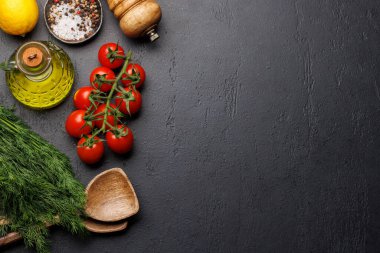 Yemek sahnesi: kiraz domatesleri, otlar ve baharatlar masada. Kopyalama alanı olan düz