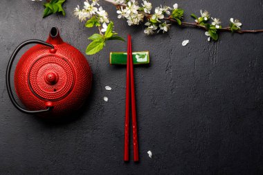 Kiraz çiçeği dalı ve yemek çubuklarıyla süslenmiş masa, Japon yemek kültürünün somut örneği, geniş bir kopya alanı sağlıyor.