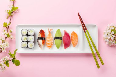 Masadaki suşi tabağı kiraz çiçeği dalıyla süslenmiş ve yemek çubukları Japon yemek kültürünün simgesi.