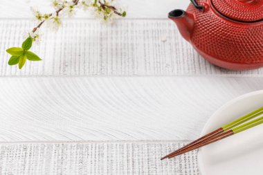 Kiraz çiçeği dalı ve yemek çubuklarıyla süslenmiş masa, Japon yemek kültürünün somut örneği, geniş bir kopya alanı sağlıyor.
