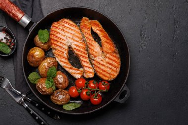 Izgara somon bifteği ve patates kızartma tavasında cızırdıyor, ağız sulandıran bir lezzet. Kopyalama alanı olan düz