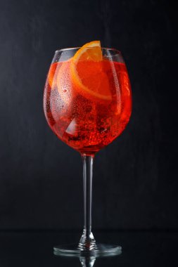 Aperol spritz kokteyli, koyu arkaplanda portakal dilimi ve buz.