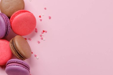 Çeşitli renkte badem kurabiyeleri. Aşk tatlıları pembe arkaplanda fotokopi alanı ile