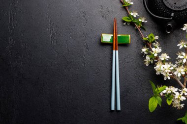 Kiraz çiçeği dalı ve yemek çubuklarıyla süslenmiş masa, Japon yemek kültürünün somut örneği, geniş bir kopya alanı sağlıyor.