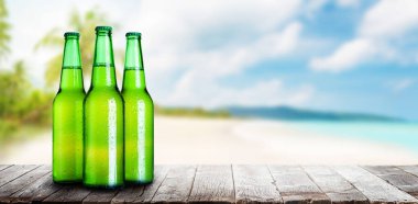 Büyüleyici bir deniz ve plaj arka planına sahip bir masada bira, rahatlamanın özünü yakalıyor.