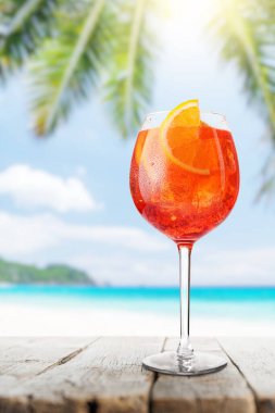 Bir bardak Aperol Spritz çarpıcı bir deniz ve plaj geçmişi olan bir masada, bir yaz günü için mükemmel.