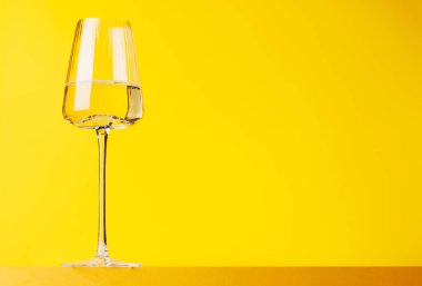 Şampanya zarafeti, parlak sarı arka planda köpüklü şarap kadehi. Kopyalama alanı ile