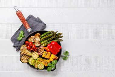 Kızartma tavasında çeşitli ızgara sebzeler, renkli ve sağlıklı bir yemek sergileniyor. Kopyalama alanı olan düz