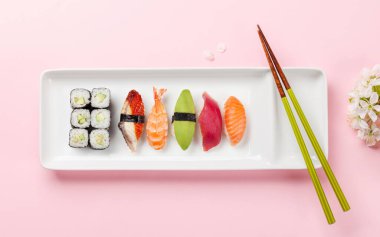 Masadaki suşi tabağı kiraz çiçeği dalıyla süslenmiş ve yemek çubukları Japon yemek kültürünün simgesi.