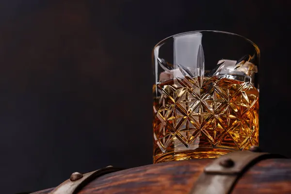 stock image Whiskey glass with ice on a rustic barrel, a classic sip. With copy space