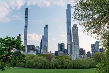 Manhattan gökdelenleri ve gün batımında Central Park çayırları