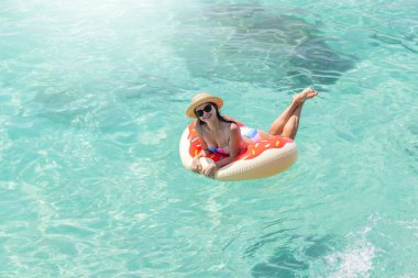 Şişme donut yüzüğüyle denizde dinlenen güzel genç bir kadın. Yaz tatili