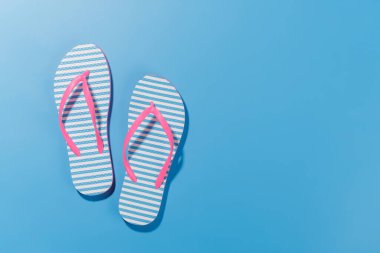 Parlak arka planda parmak arası terliklerle hareketli bir yaz tatili sahnesi, neşeli ve tropikal bir atmosferi çağrıştırıyor. Kopyalama alanı olan düz