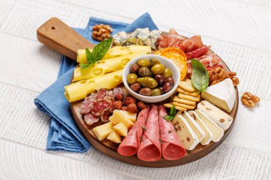 Tahta bir tahtanın üzerinde çeşitli peynir ve et çeşitleri var. Antipasto yaymak için mükemmel, çeşitli aromalar ve dokular sergiliyor.