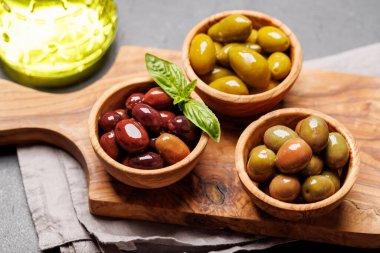 Farklı renkler, dokular ve tatlar içeren çeşitli zeytinlerden oluşan bir kasede sunulmuştur.