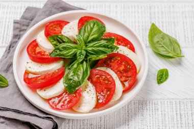Canlı ve iştah açıcı bir Caprese antipasti. İçinde olgun domatesler, taze mozarella ve aromatik fesleğen yaprakları var.