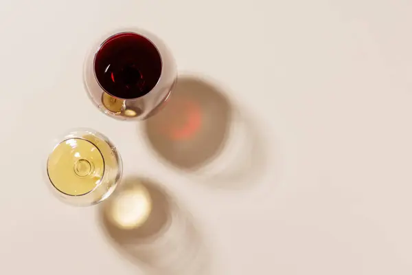 stock image Two wine glasses arranged on a bright background. The hard light creates sharp shadows, adding a dramatic effect to the scene, emphasizing the shapes