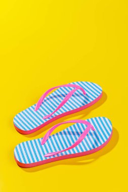 Parlak bir arka planda parmak arası terliklerle hareketli bir yaz tatili sahnesi, kopya uzayı ile eğlenceli ve tropikal bir atmosferi çağrıştırıyor.