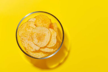 Parlak sarı bir zemin üzerine kurulmuş canlı bir patates cipsi sergilenen fotoğraf fotokopi uzayı ile eğlenceli ve iştah açıcı bir sahne yaratıyor.