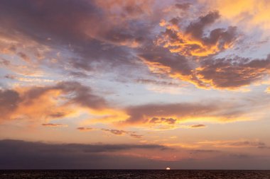 Karanlık, dönen bulutlarla dolu dramatik ve karamsar bir günbatımı gökyüzü gizem ve atmosfer hissi uyandırıyor.