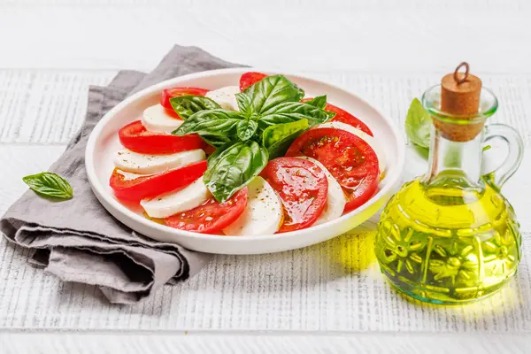 Canlı ve iştah açıcı bir Caprese antipasti. İçinde olgun domatesler, taze mozarella ve aromatik fesleğen yaprakları var.