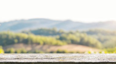 Ön planda boş bir ahşap masa. Arka planda güneşli bir üzüm bağı var. Ürünlerin sergilenmesi için kopya alanı ile mükemmel bir şablon sunuyor.