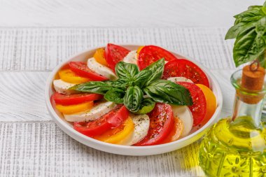 Canlı ve iştah açıcı bir Caprese antipasti. İçinde olgun domatesler, taze mozarella ve aromatik fesleğen yaprakları var.