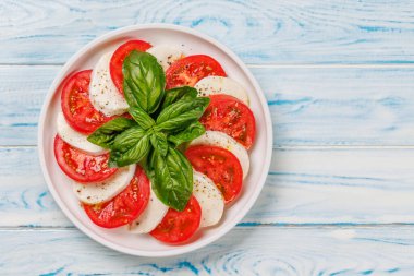 Canlı ve iştah açıcı bir Caprese antipasti sergisi içinde olgun domatesler, taze mozarella ve aromatik fesleğen yaprakları var. Kopyalama alanı olan düz