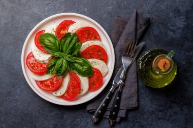 Canlı ve iştah açıcı bir Caprese antipasti. İçinde olgun domatesler, taze mozarella ve aromatik fesleğen yaprakları var.
