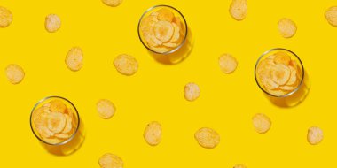 Parlak bir patates cipsi sergisi pürüzsüz sarı bir arka plana saçılmış. Atıştırmalık temalı bir konsept için mükemmel.