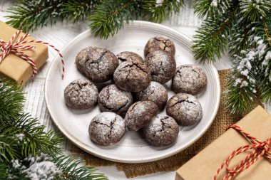 Noel süsleri ve köknar ağacıyla bir tabakta düzenlenmiş çeşitli Noel kurabiyeleri.