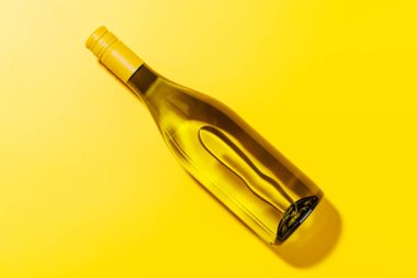 Beyaz bir şarap şişesi düz konum sarı arka planda düz düz düz bir şekilde, canlı ve göz alıcı bir sahne oluşturur