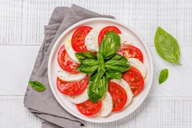Canlı ve iştah açıcı bir Caprese antipasti sergisi içinde olgun domatesler, taze mozarella ve aromatik fesleğen yaprakları var. Kopyalama alanı olan düz