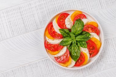 Canlı ve iştah açıcı bir Caprese antipasti sergisi içinde olgun domatesler, taze mozarella ve aromatik fesleğen yaprakları var. Kopyalama alanı olan düz