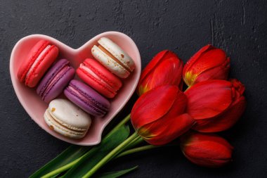 Kırmızı laleler ve canlı kurabiyeler kalp şeklindeki bir kaseyi doldurur. Kutlamalar ve neşeli anlar için mükemmel ve büyüleyici bir sahne sunar.