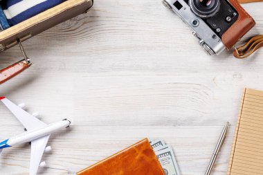 Elbiseli bir seyahat çantası, güneş şapkası, parmak arası terlik, ve ahşap arka planda düzenlenmiş bir kamera, düz konum tarzı, ürününüz için fotokopi alanı ile birlikte.