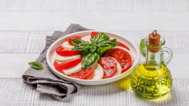 Canlı ve iştah açıcı bir Caprese antipasti. İçinde olgun domatesler, taze mozarella ve aromatik fesleğen yaprakları var.